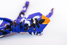 Liberty Of London Cotton Bow Tie With A Poppy Floral Design. A Orange Poppy dances on a solid blue background and abstract black and white floral patterns to tone down this bold slim diamond tip design. 