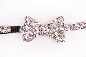 black skulls and bones pattern on this white cotton bow tie with a butterfly design.