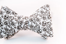 black skulls and bones pattern on this white cotton bow tie with a butterfly design.